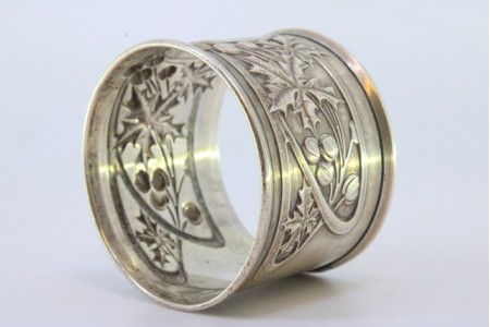 Argola de guardanapo em prata com motivos florais relevados envolvendo cartela para monograma.